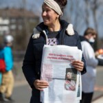 Frau hält Zeitung mit ihrem Artikel in die Kamera