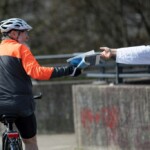 Radfahrer nimmt Zeitung während der Fahrt entgegen